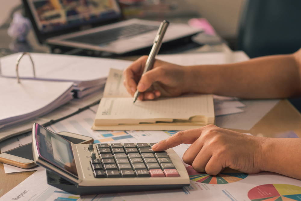 vue sur un bureau où une personne utilise une calculatrice et un agend